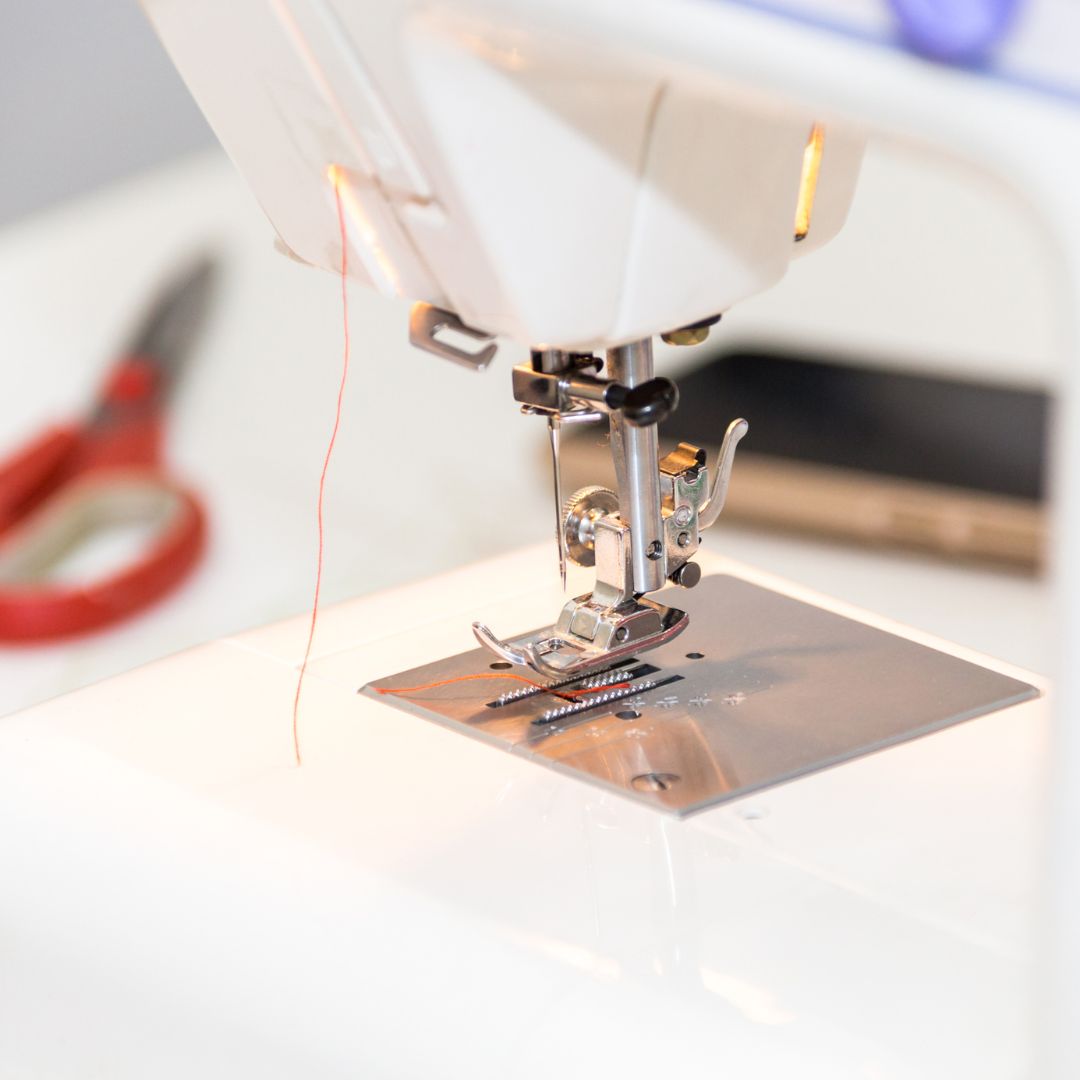 image of a sewing machine foot and needle with thread hanging loose