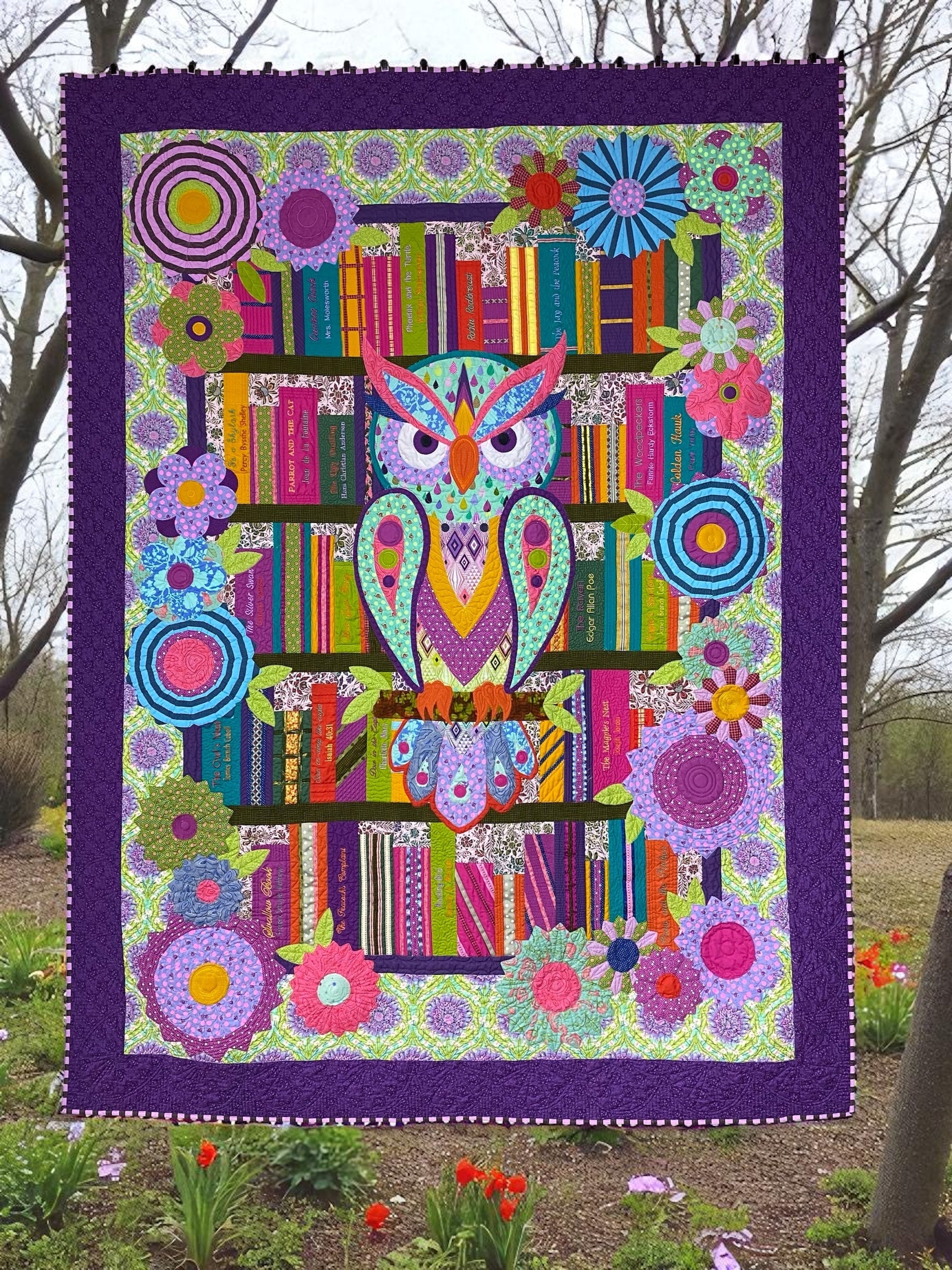 Colorful owl quilt with floral patterns displayed outdoors.